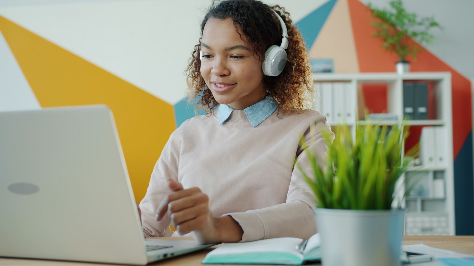 Learner using headphones while working on a laptop