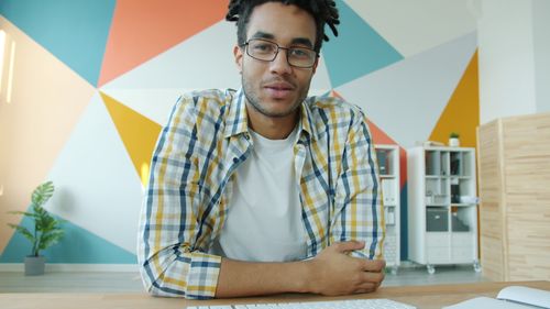 Free Confident young adult in a modern office with geometric wall design, looking at the camera. Stock Photo