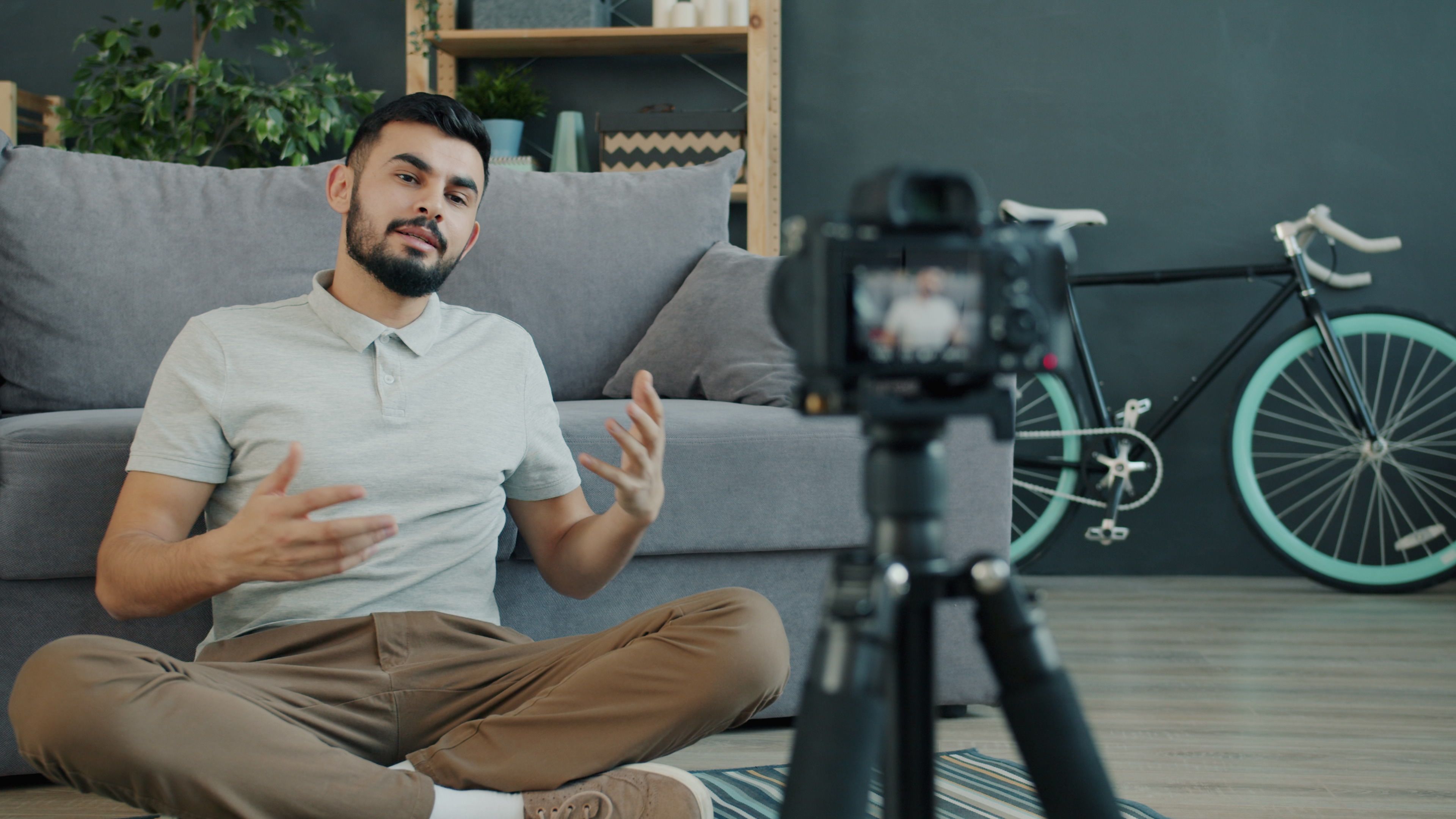 Casual young man filming vlog at home with camera, illustrating influencer lifestyle.