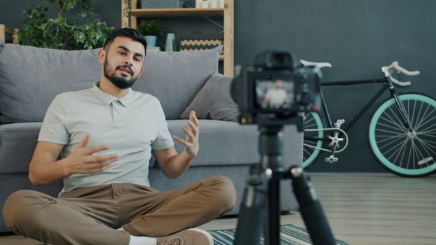 Casual young man filming vlog at home with camera, illustrating influencer lifestyle.