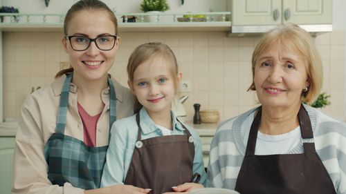 Free A joyful family of three generations, grandmother, mother, and daughter, bonding in a cozy kitchen. Stock Photo