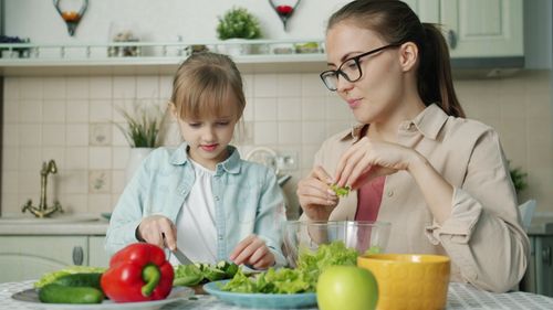 Free A mother and daughter cutting vegetables for a healthy salad at home. Stock Photo