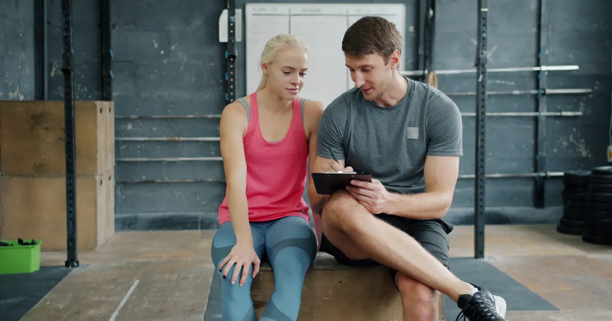 A personal trainer talking through a plan with a client in a gym