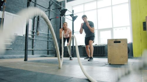 Free Two adults engaged in an intense workout with battle ropes at a gym. Stock Photo