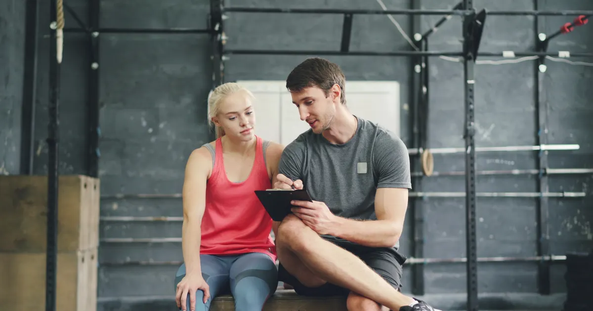 A trainer taking notes while a client sits and talks