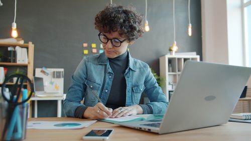 Free Young adult working diligently in modern office setting. Stock Photo