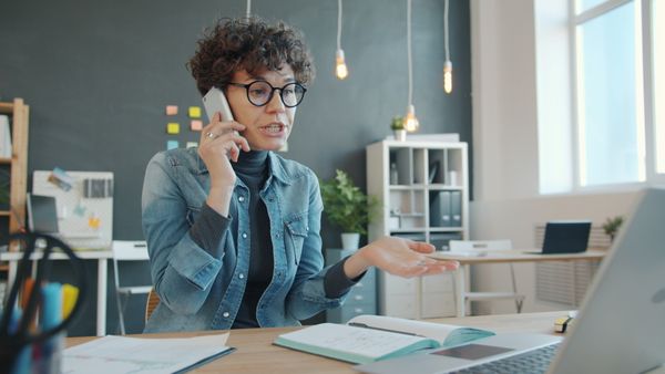 Professional woman engaged in a phone call at a contemporary office desk.