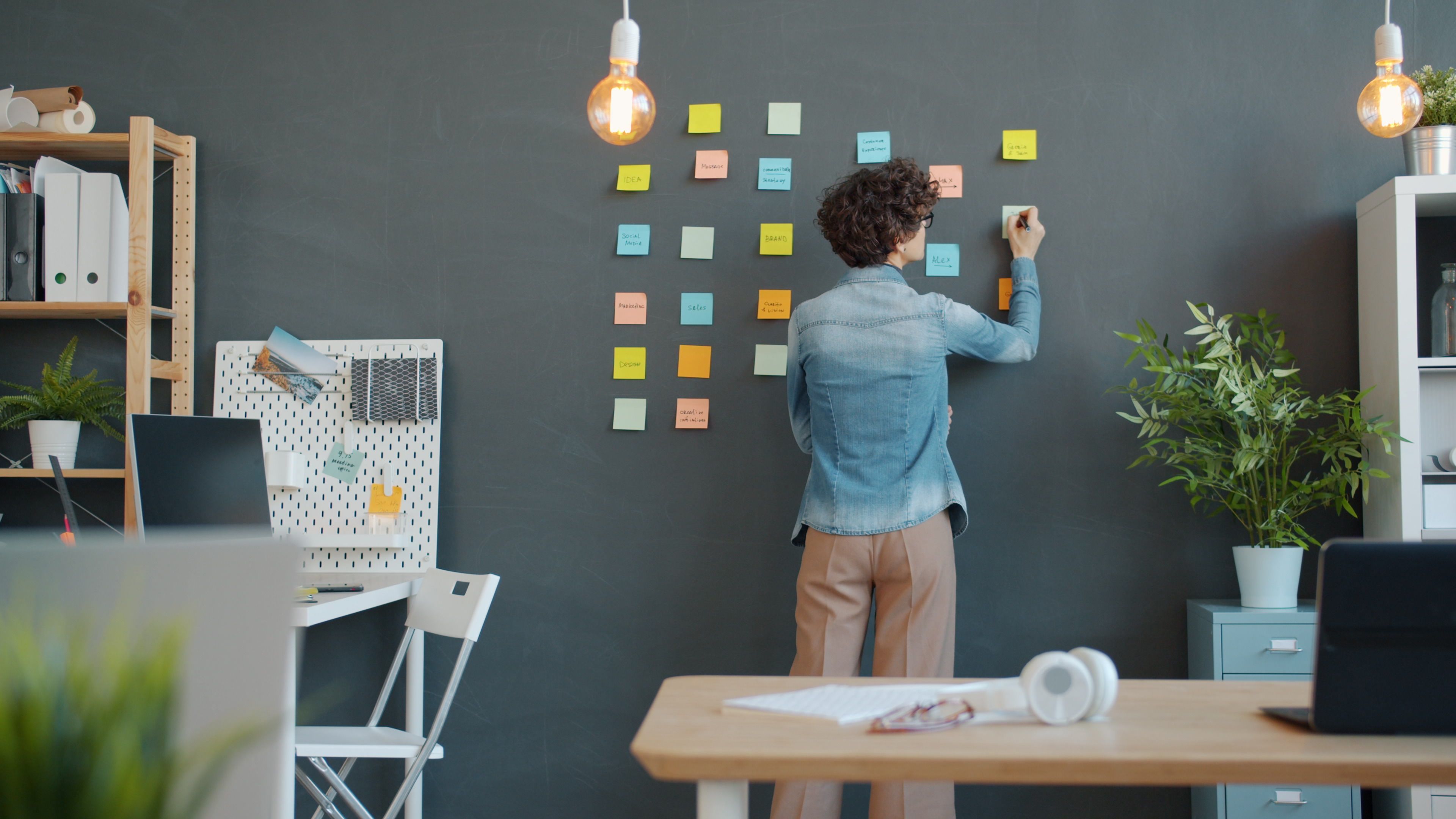 Woman arranging sticky notes on her office wall.
