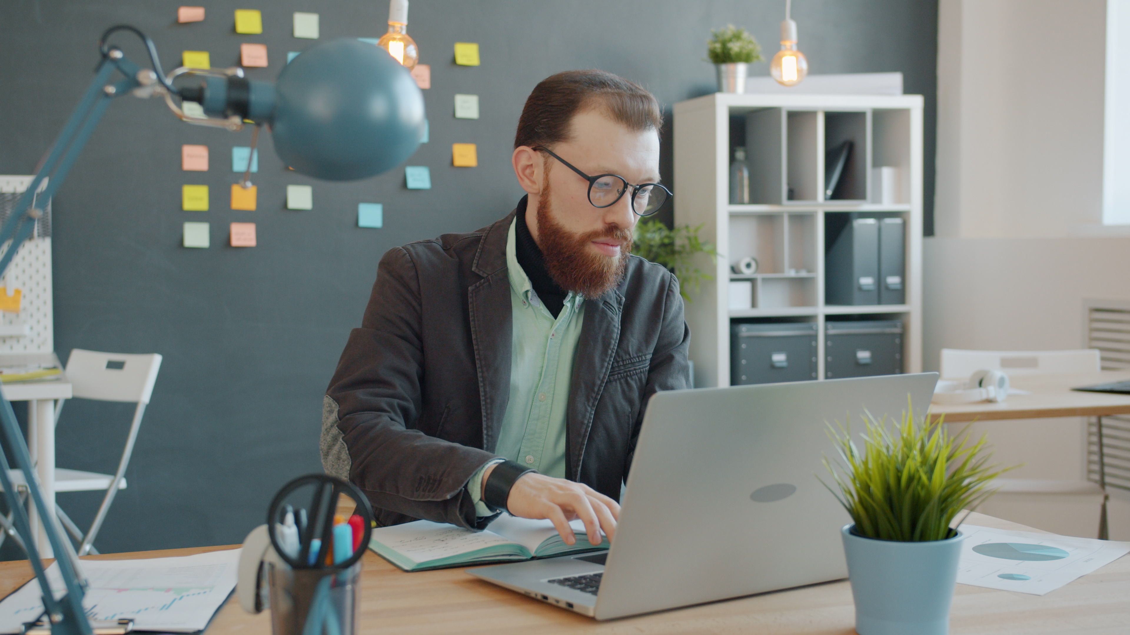Focused young professional working on a laptop in a stylish, modern office setting.
