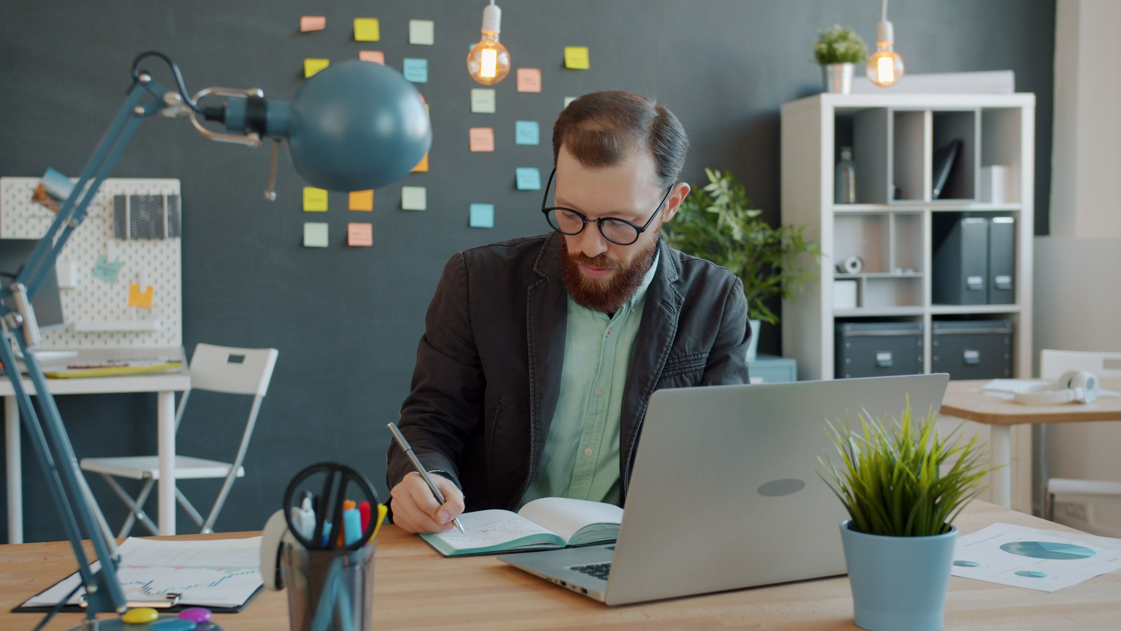 Business professional working at a desk with a laptop, taking notes in a creative office space. - The Functional vs. Chronological Debate: The Hybrid Format That Dominates 2026 Hiring