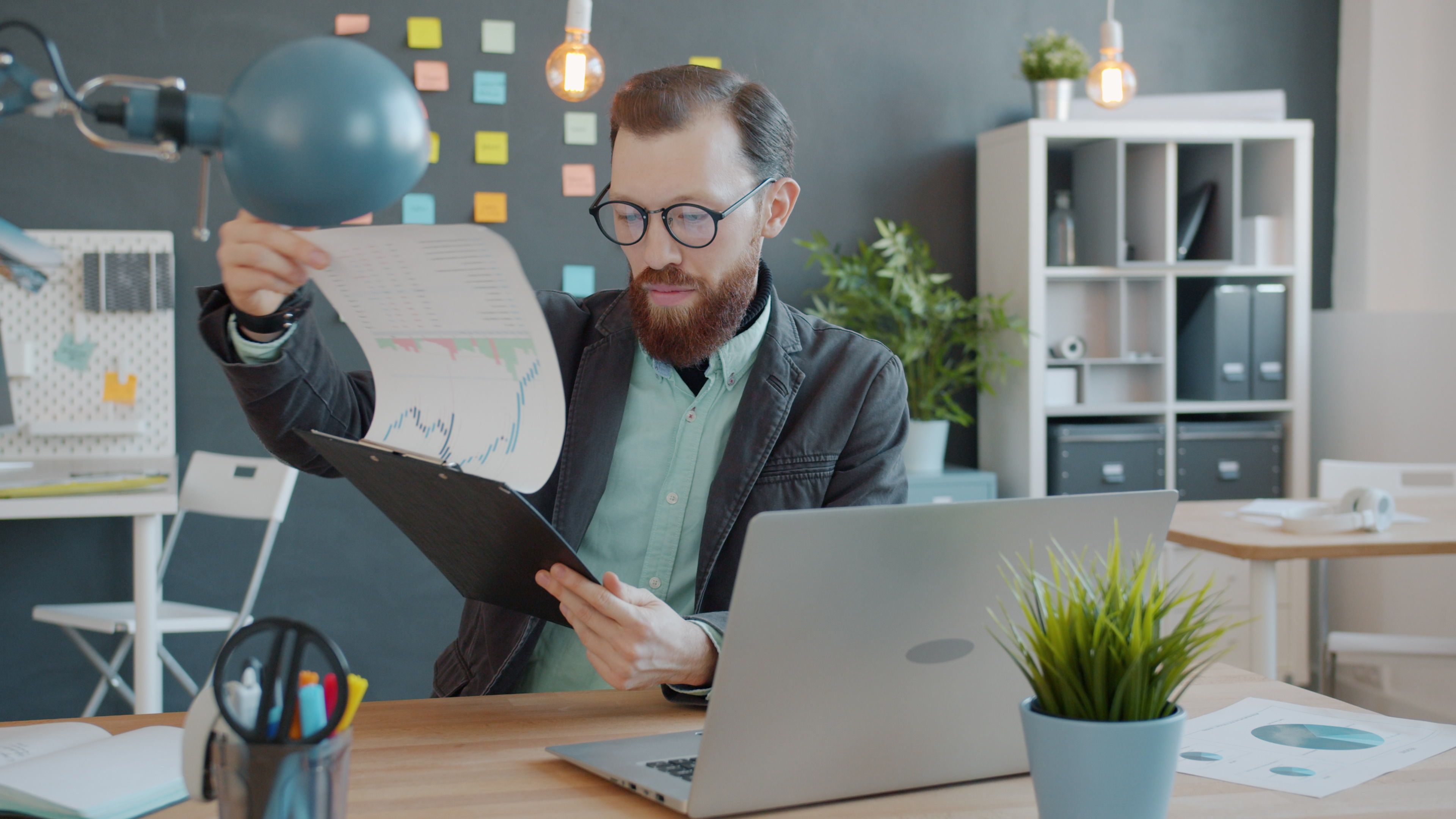 Business owner looking at rising growth chart on laptop in modern office