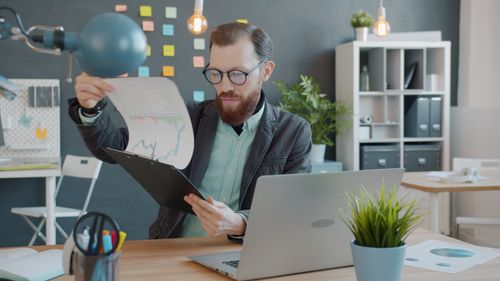 Free Focused man reviewing financial charts at modern office desk. Stock Photo