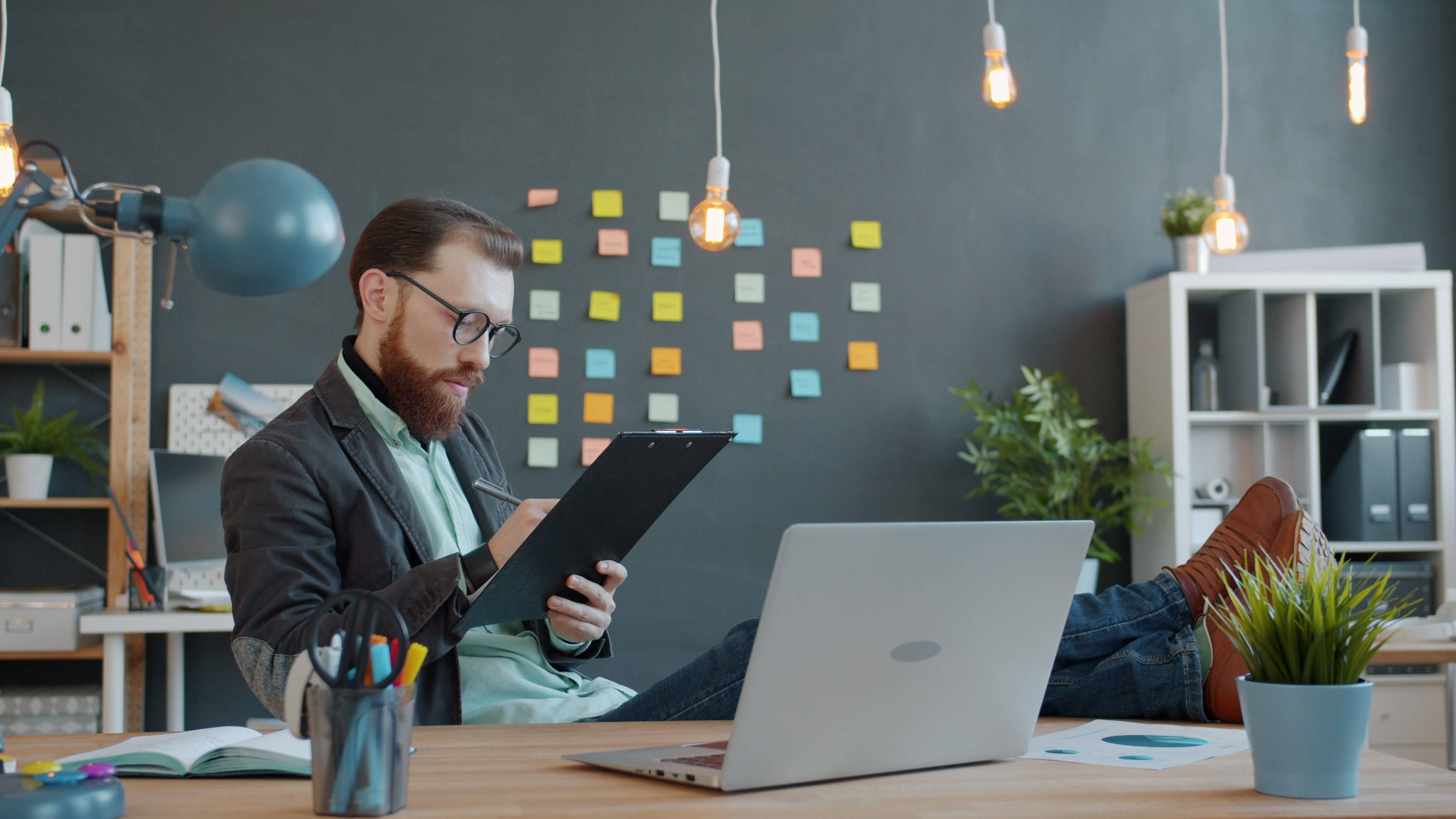 Businessman with clipboard in modern office, generating creative ideas with sticky notes background.