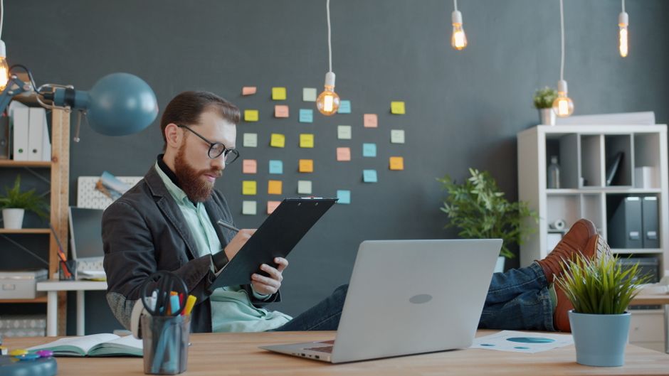 Businessman with clipboard in modern office, generating creative ideas with sticky notes background.