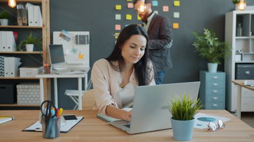 Free Two professionals working in a creative office with laptops and sticky notes. Stock Photo