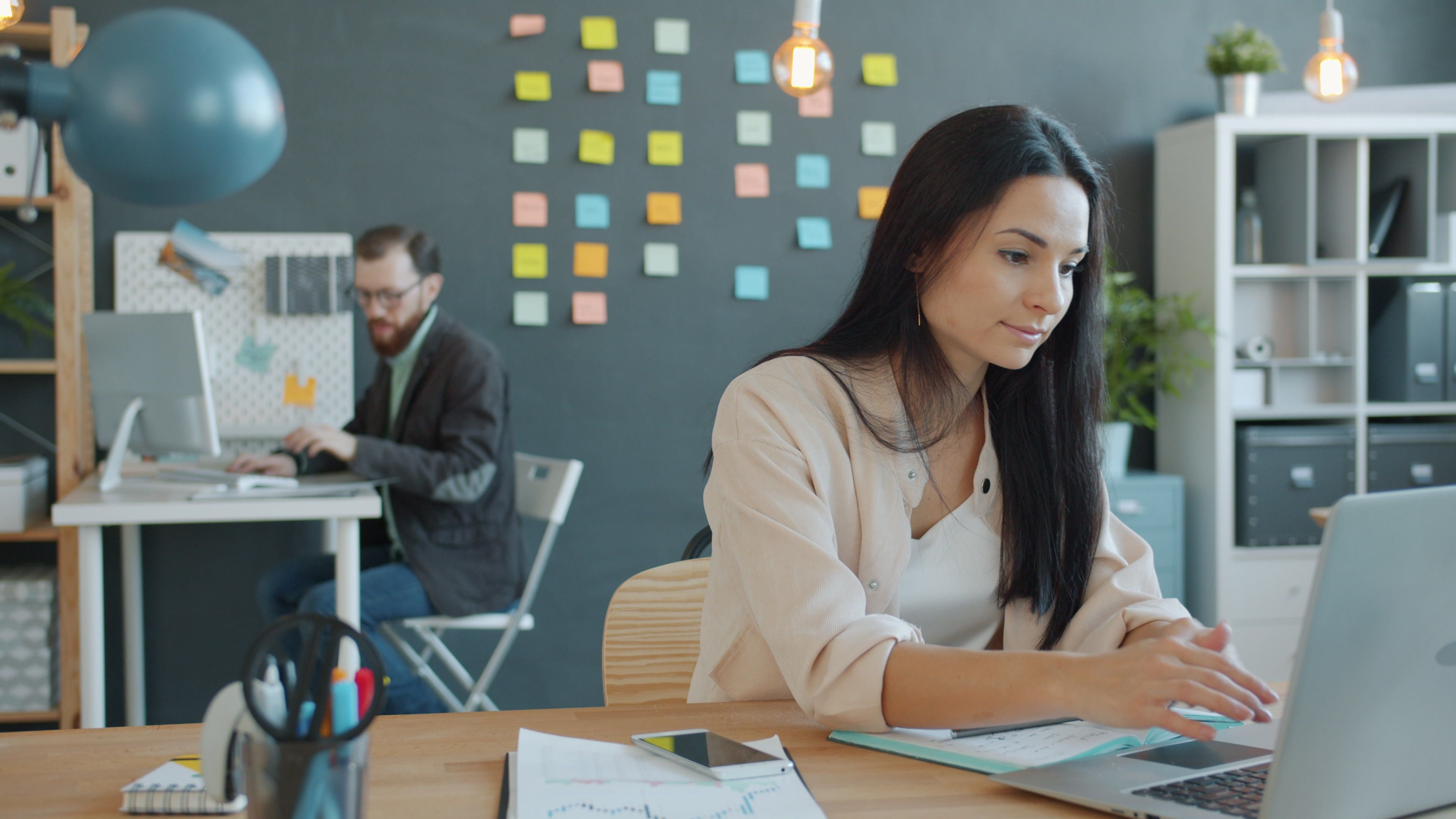 Young professionals working in a modern office with laptops and diverse decor.