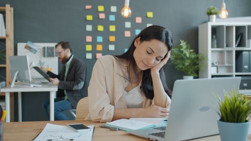Free Young woman focusing on laptop work in a contemporary office setting. Stock Photo