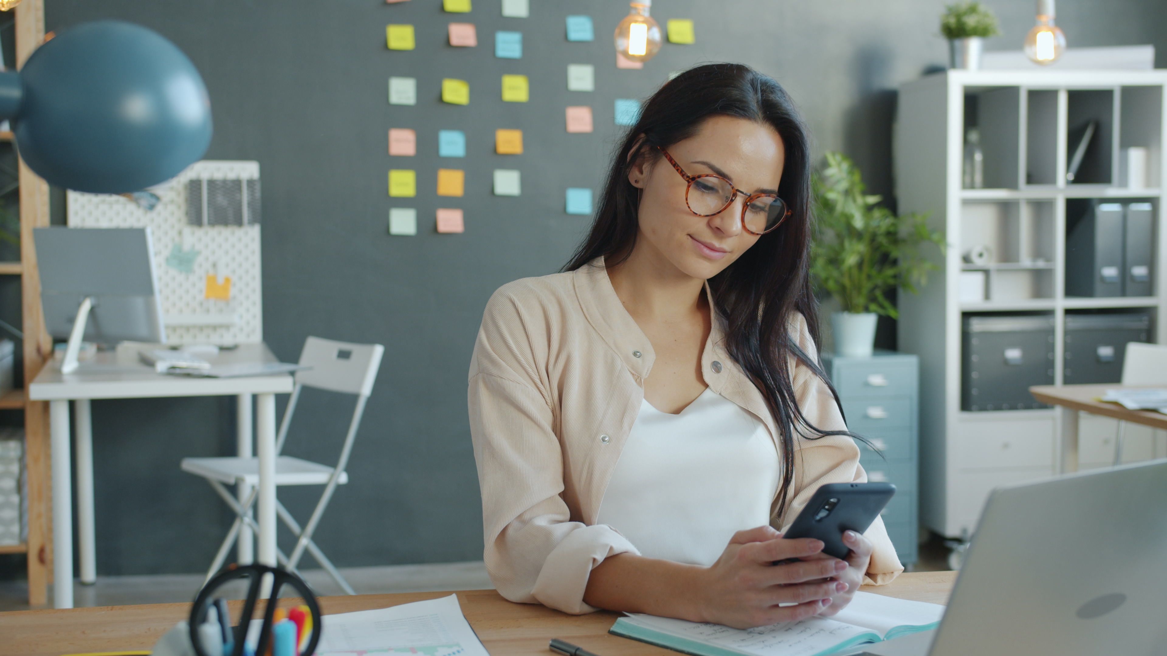 Woman checking her smartphone at her desk.