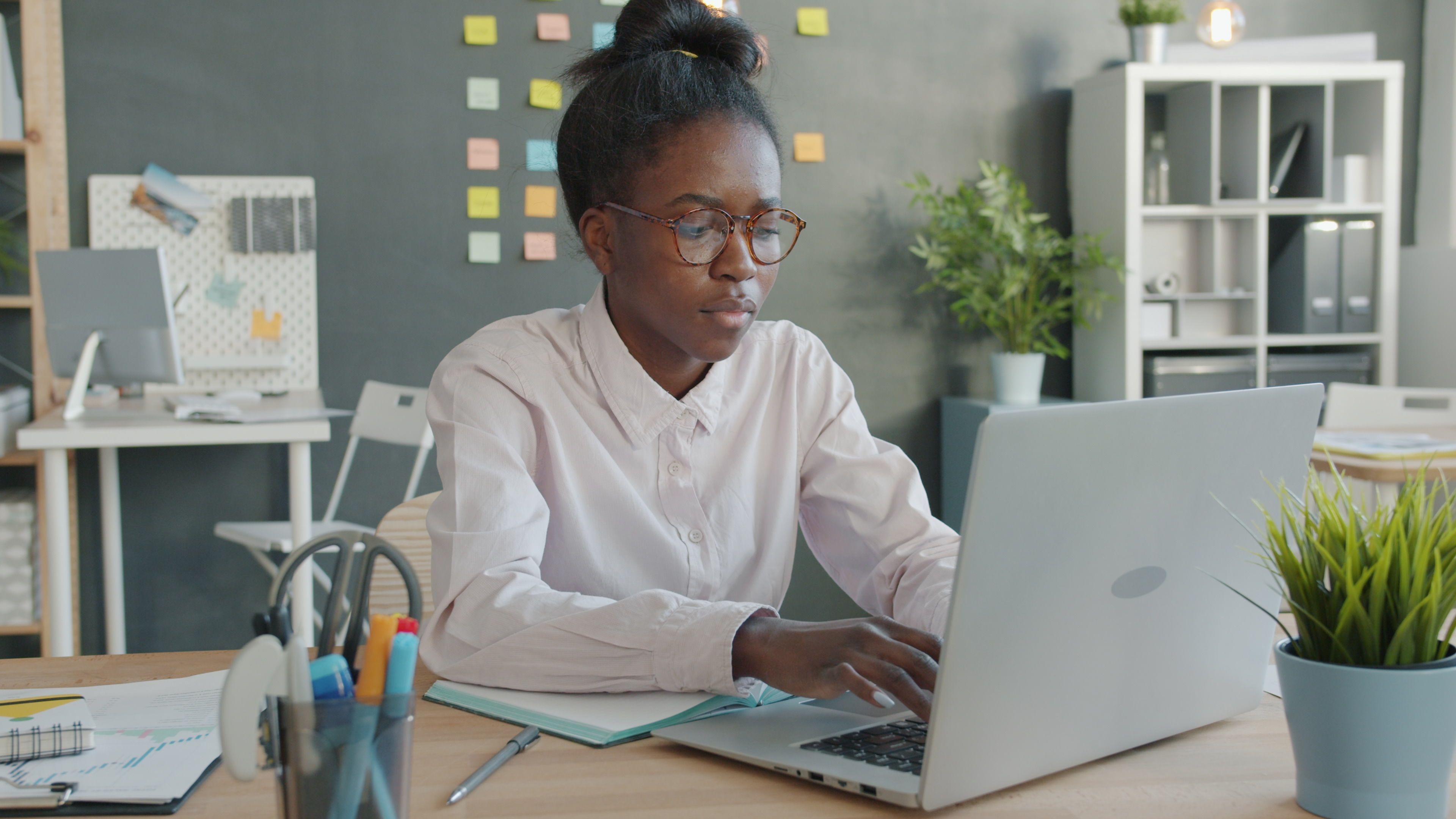 Focused young woman working on her laptop in a modern office setting.