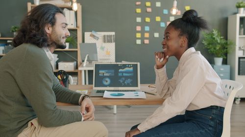 Free Two colleagues discussing data analytics in a creative office space. Stock Photo