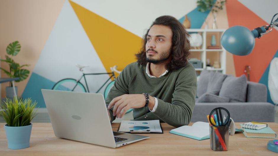 A thoughtful young man working on a laptop in a creatively designed office. A thoughtful young man working on a laptop in a creatively designed office.