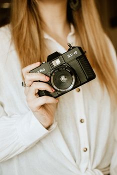 Close-up of a woman holding a vintage NX-40 camera in a cozy setting.