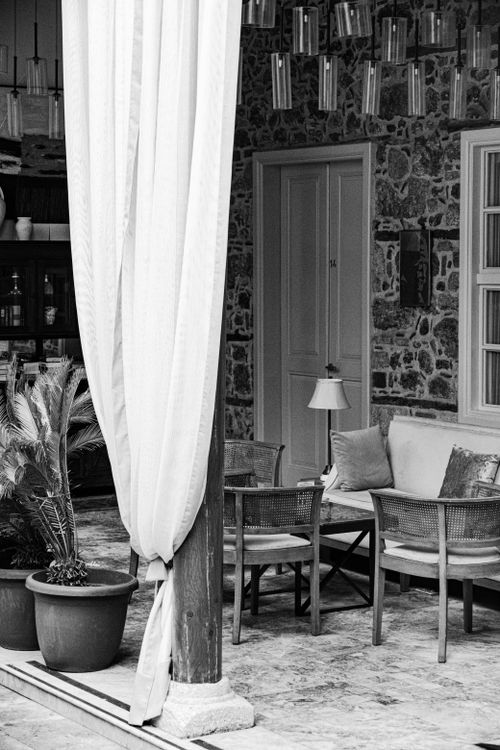 Free Black and white image of a stylish outdoor patio featuring wicker chairs and stone wall. Stock Photo