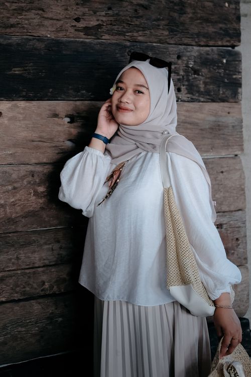 Free Fashionable woman in hijab standing against a rustic wooden backdrop, exuding confidence. Stock Photo