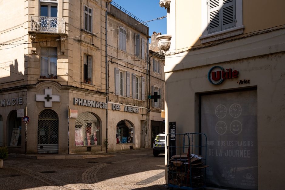 A sunny day on a quaint street in Arles, showcasing historic architecture and local shops.