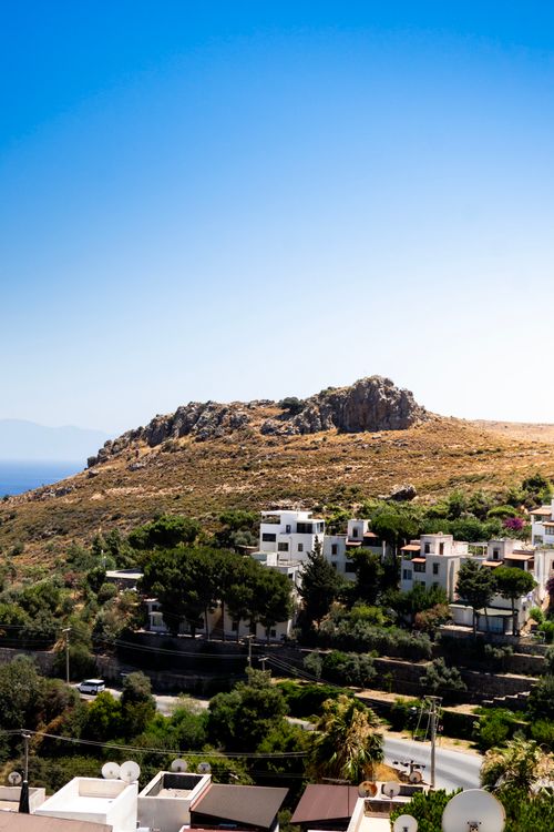 Free Picturesque residential area on a hill with a clear blue sky, capturing a serene summer day. Stock Photo