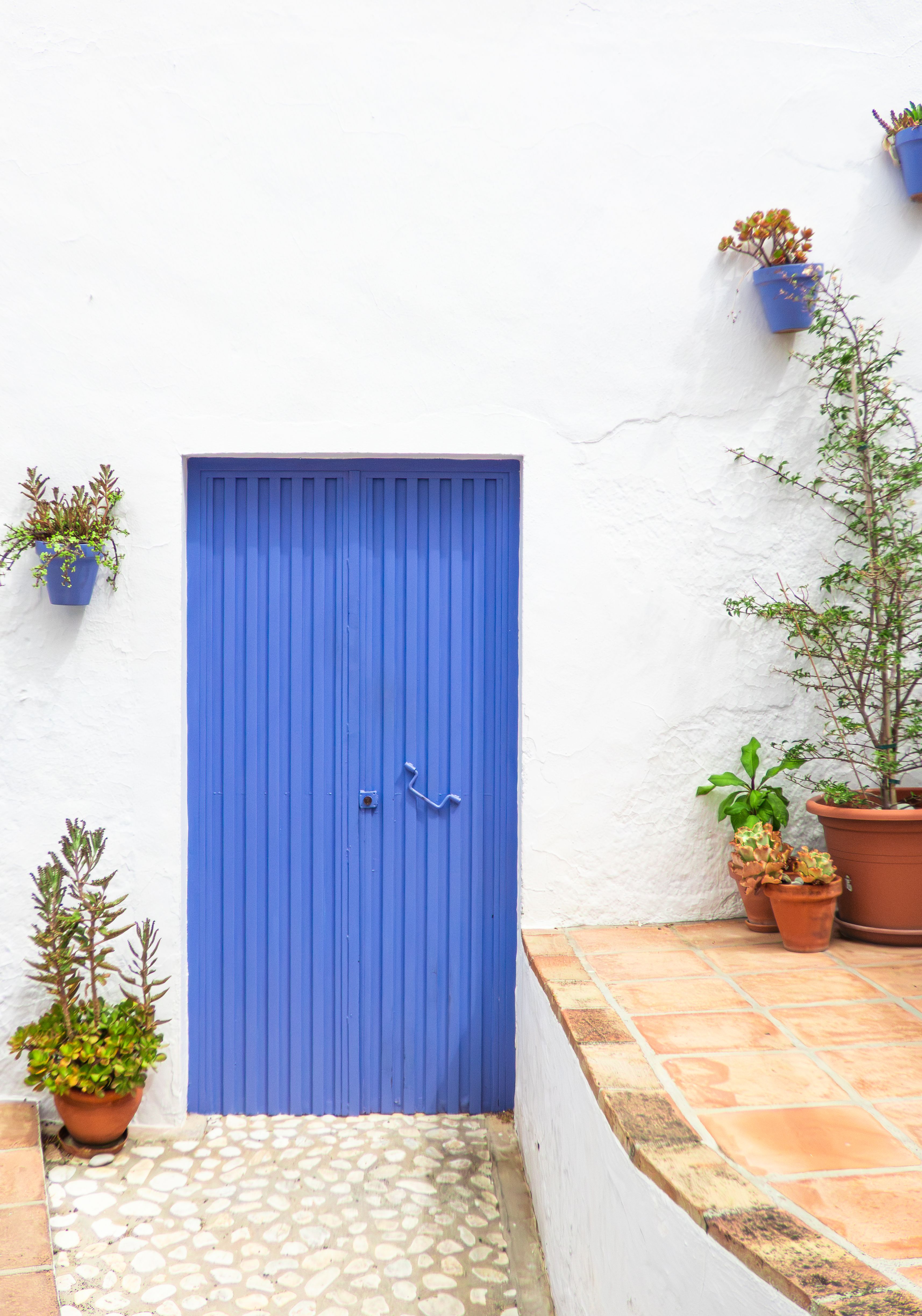Fotomural Una puerta de un azul vibrante sobre una pared encalada en Frigiliana, Andalucía, España. Encanto mediterráneo.