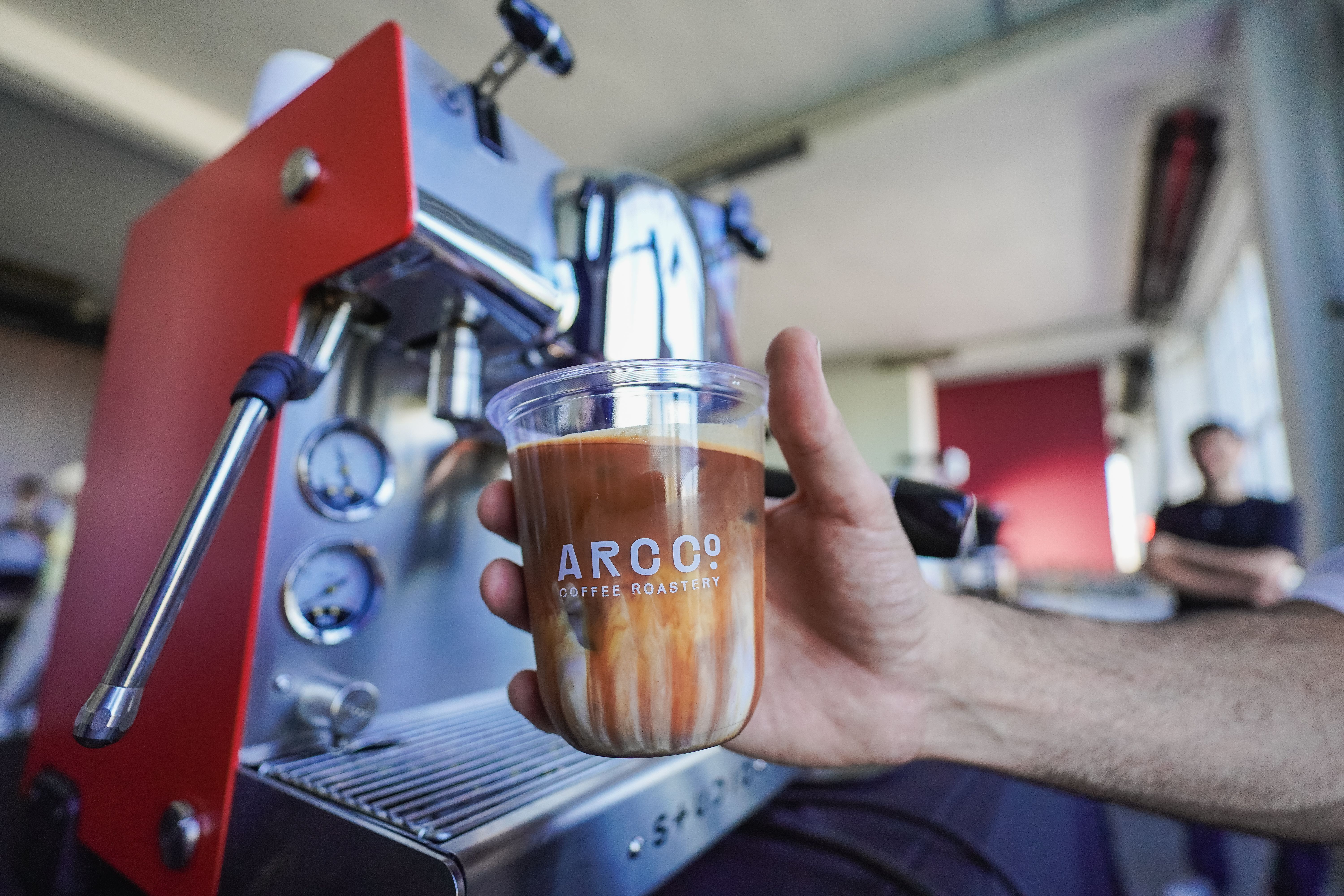 A detailed view of a coffee cup held in front of an espresso machine in a cozy cafe.