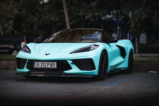 A sleek turquoise sports car parked in an urban environment, exuding luxury and speed.