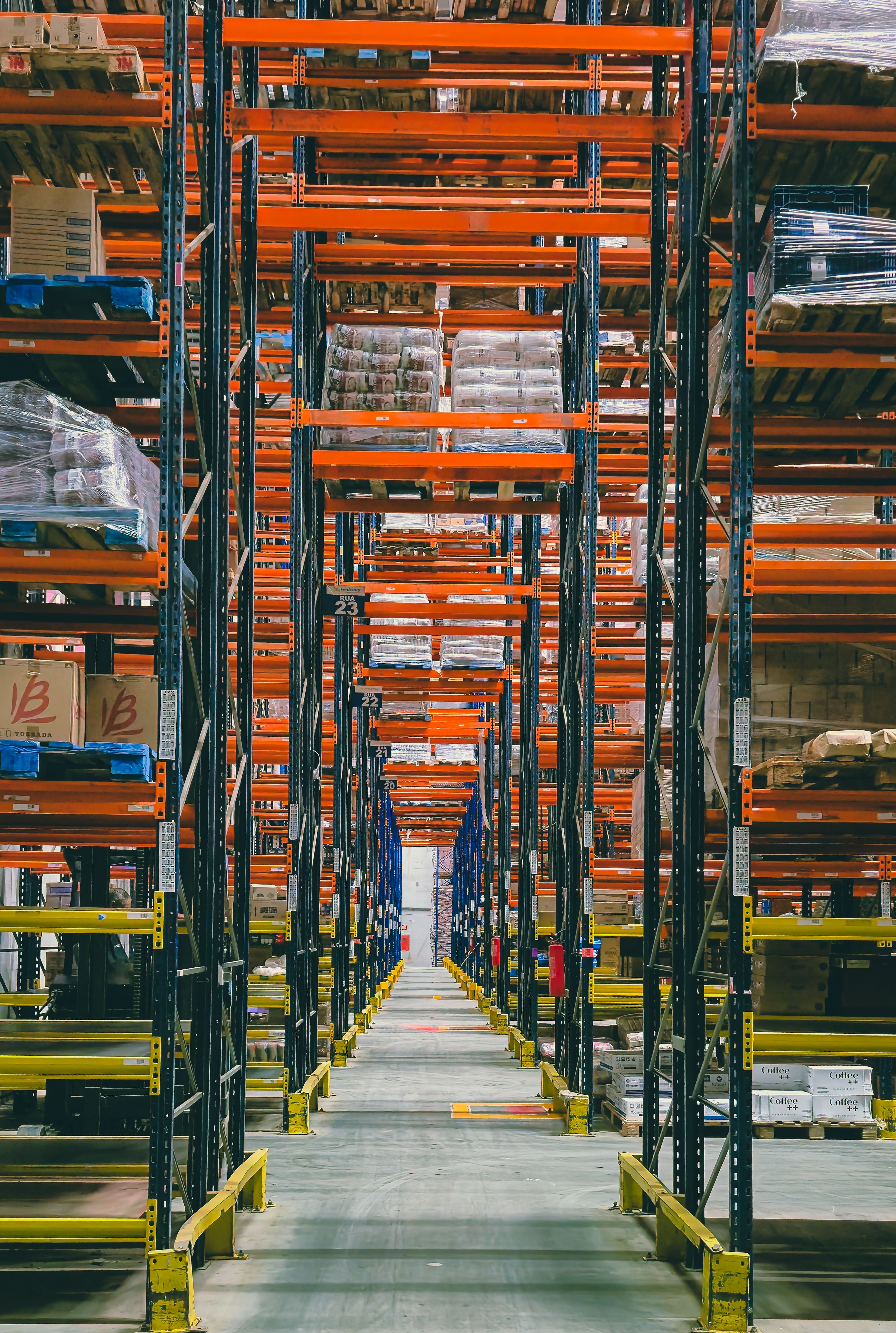 A spacious Brazilian warehouse with tall storage racks filled with packaged goods.