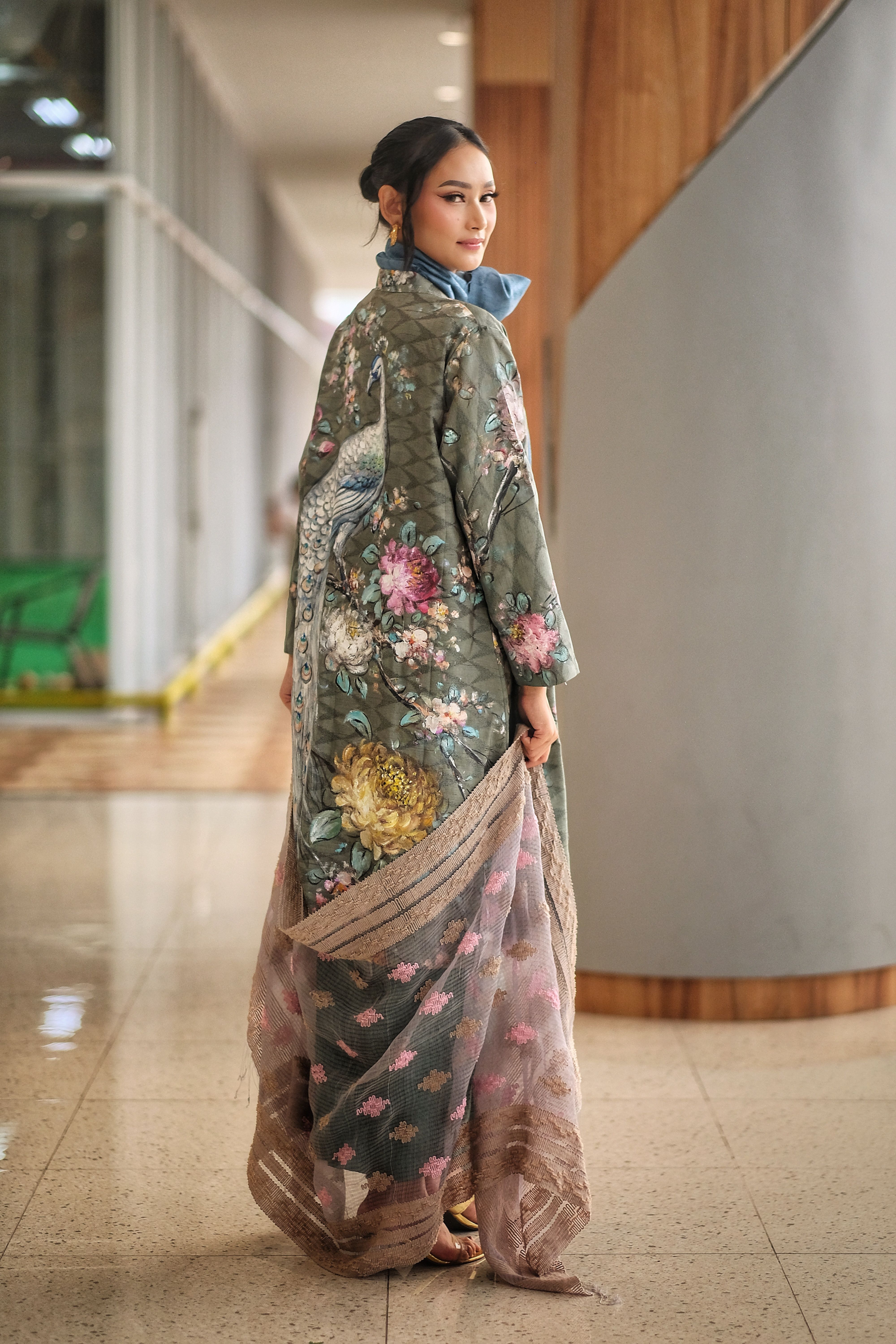 Woman in traditional Indonesian wear at a modern indoor location, showcasing elegant floral design.