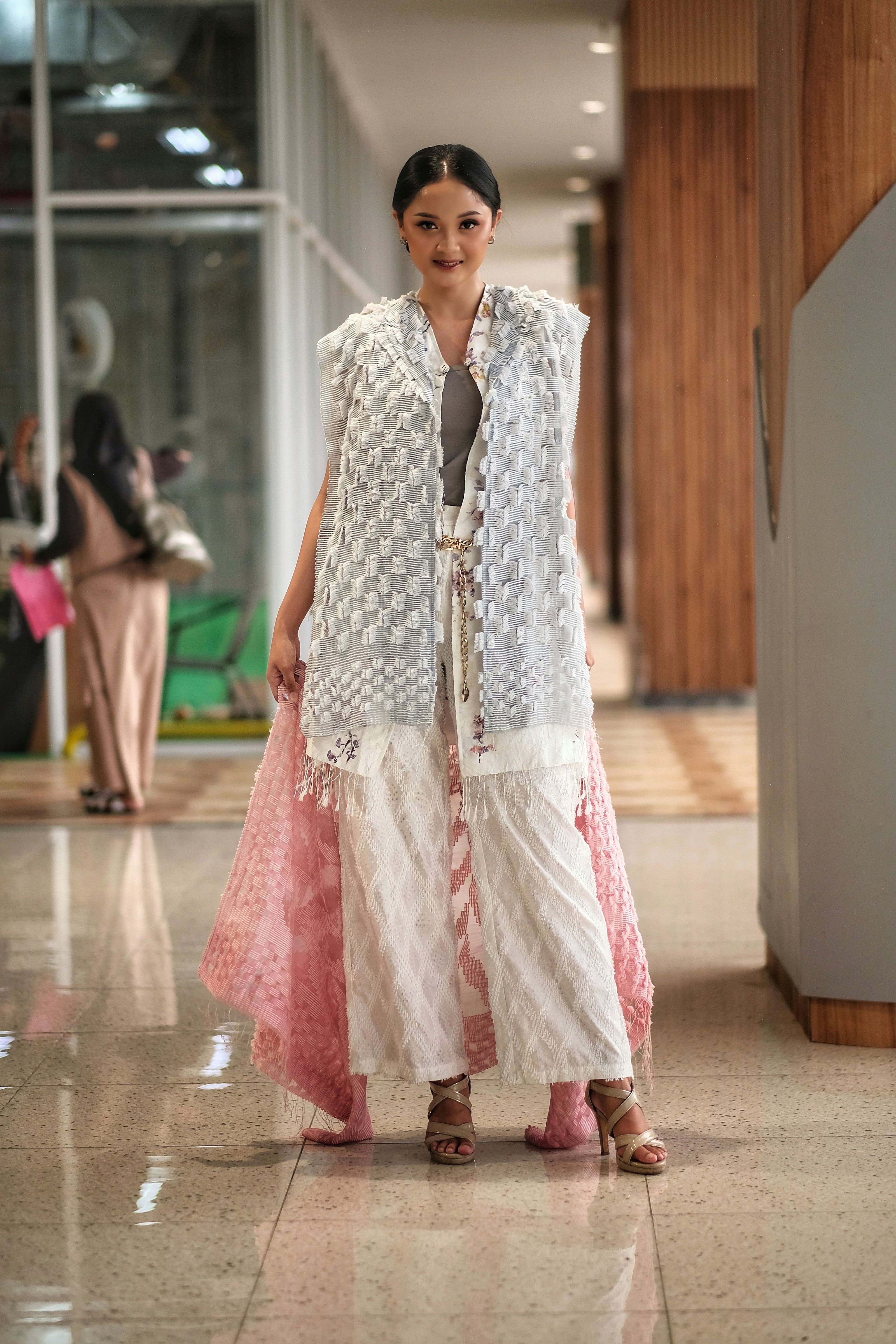 Modelo com um elegante conjunto rosa e branco caminhando em um ambiente interno em Garut, exibindo moda moderna.