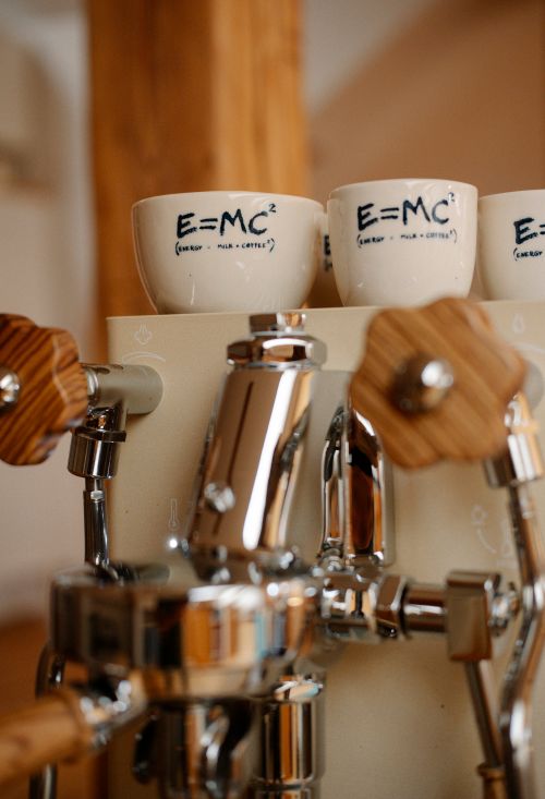 Free Espresso machine with witty E=MC2 coffee cups, blending science and coffee culture. Stock Photo