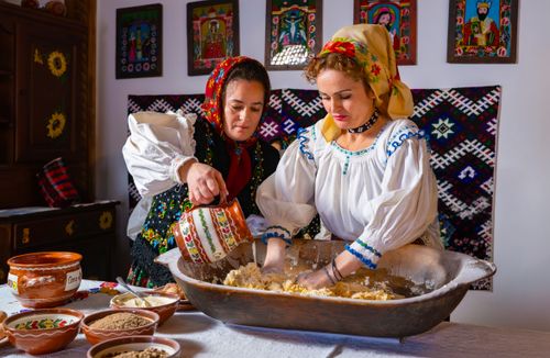 Free Two women in traditional Romanian attire preparing dough in Maramureș. Stock Photo