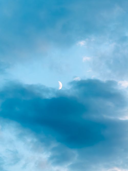 Free A tranquil sky with a crescent moon peeking through blue clouds, offering a calm visual experience. Stock Photo
