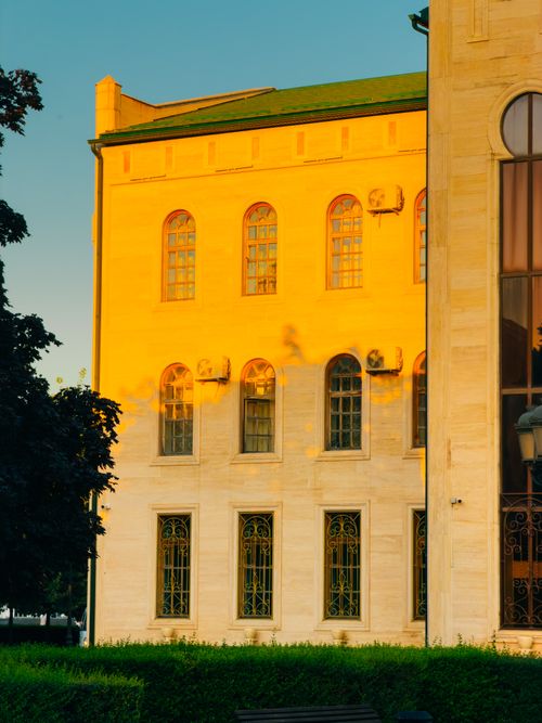 Free Golden sunset light casts shadows on a classic building's facade, highlighting intricate window designs. Stock Photo