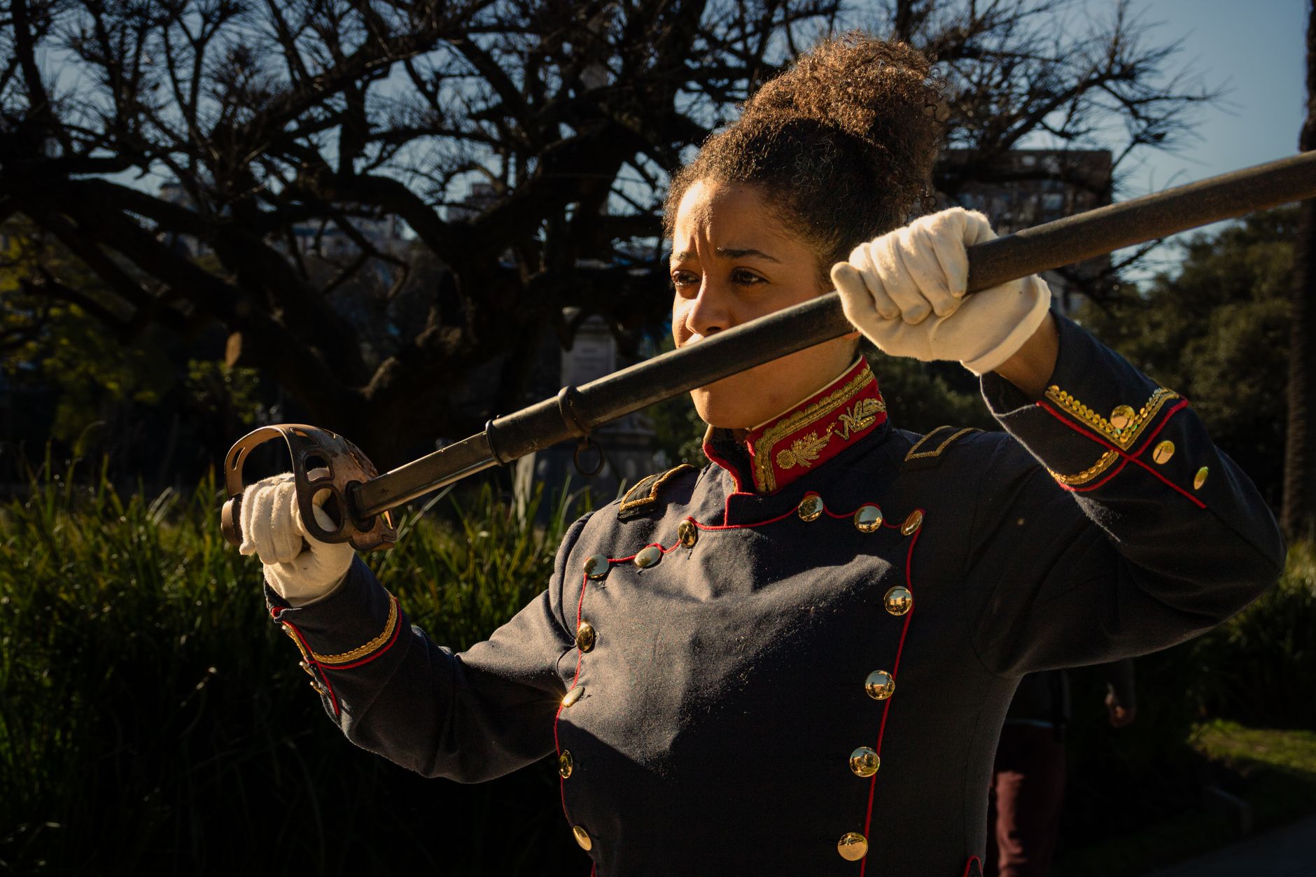 Un figurant argentin en uniforme militaire traditionnel, tenant une épée en extérieur, participe à une reconstitution historique.