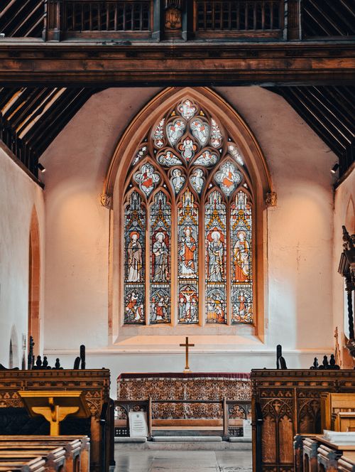 Free Elegant church interior with intricate stained glass windows, wooden pews, and altar decor. Stock Photo