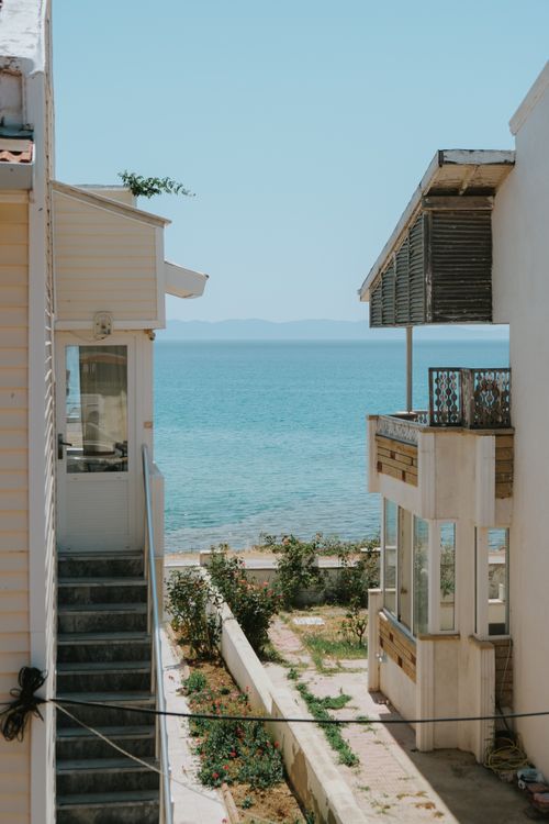 Free Tranquil seaside view between houses, showcasing a blue ocean under a clear sky. Stock Photo