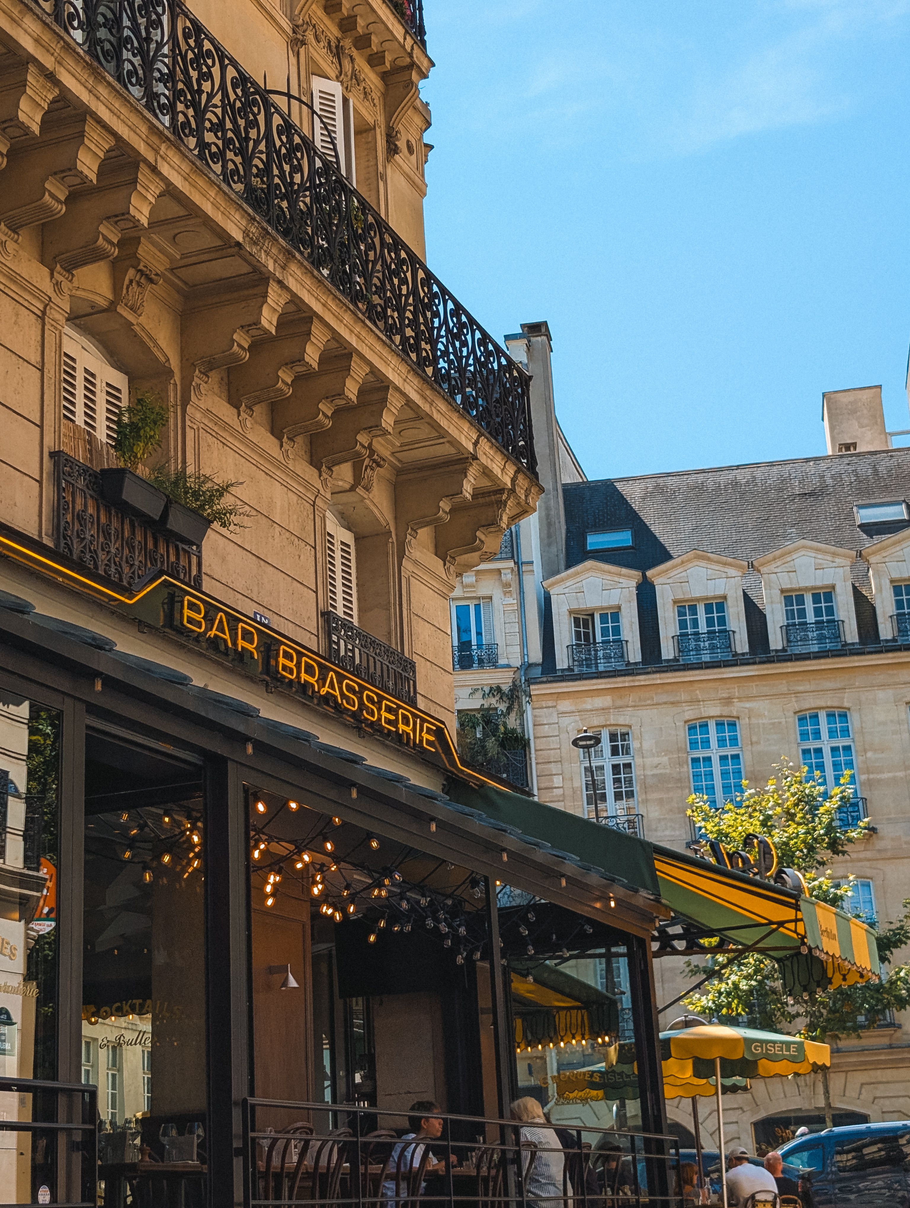 A picturesque Parisian brasserie with classic architecture under a bright blue sky.
