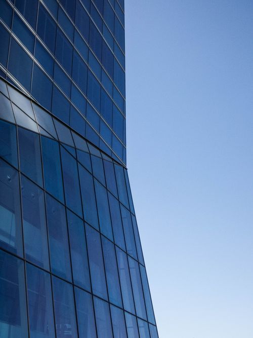 Free A modern glass building with a reflective facade under a clear blue sky in Madrid, Spain. Stock Photo