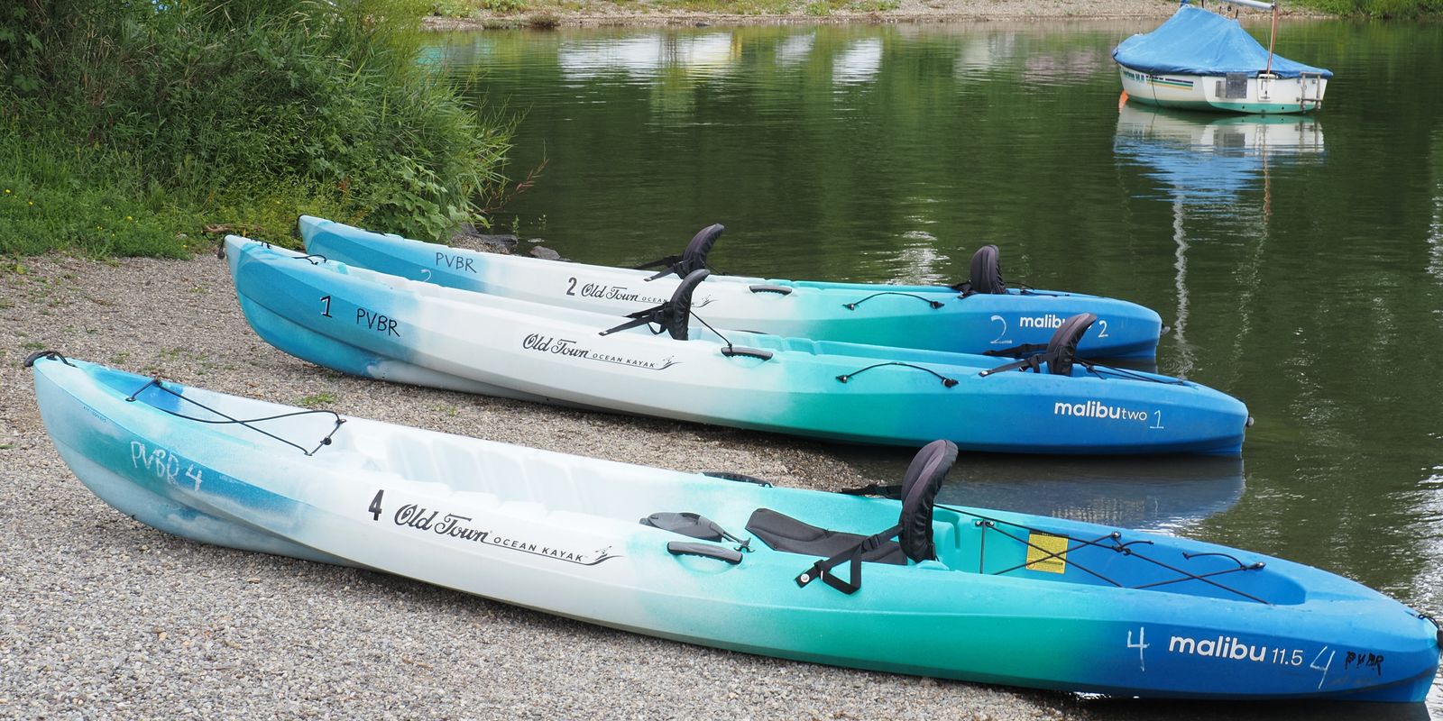 Colorful kayaks lined up beside a tranquil lake