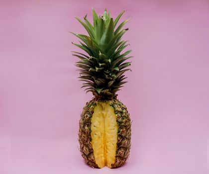柔和的粉色背景映衬着半片充满活力的菠萝，展现了其多汁的质感