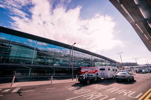 Daytime view of the modern terminal building at Dublin Airport, Ireland, with cars and buses parked outside.