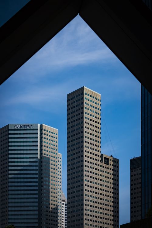 Free Tall urban skyscrapers framed by a unique triangular architecture against a blue sky. Stock Photo