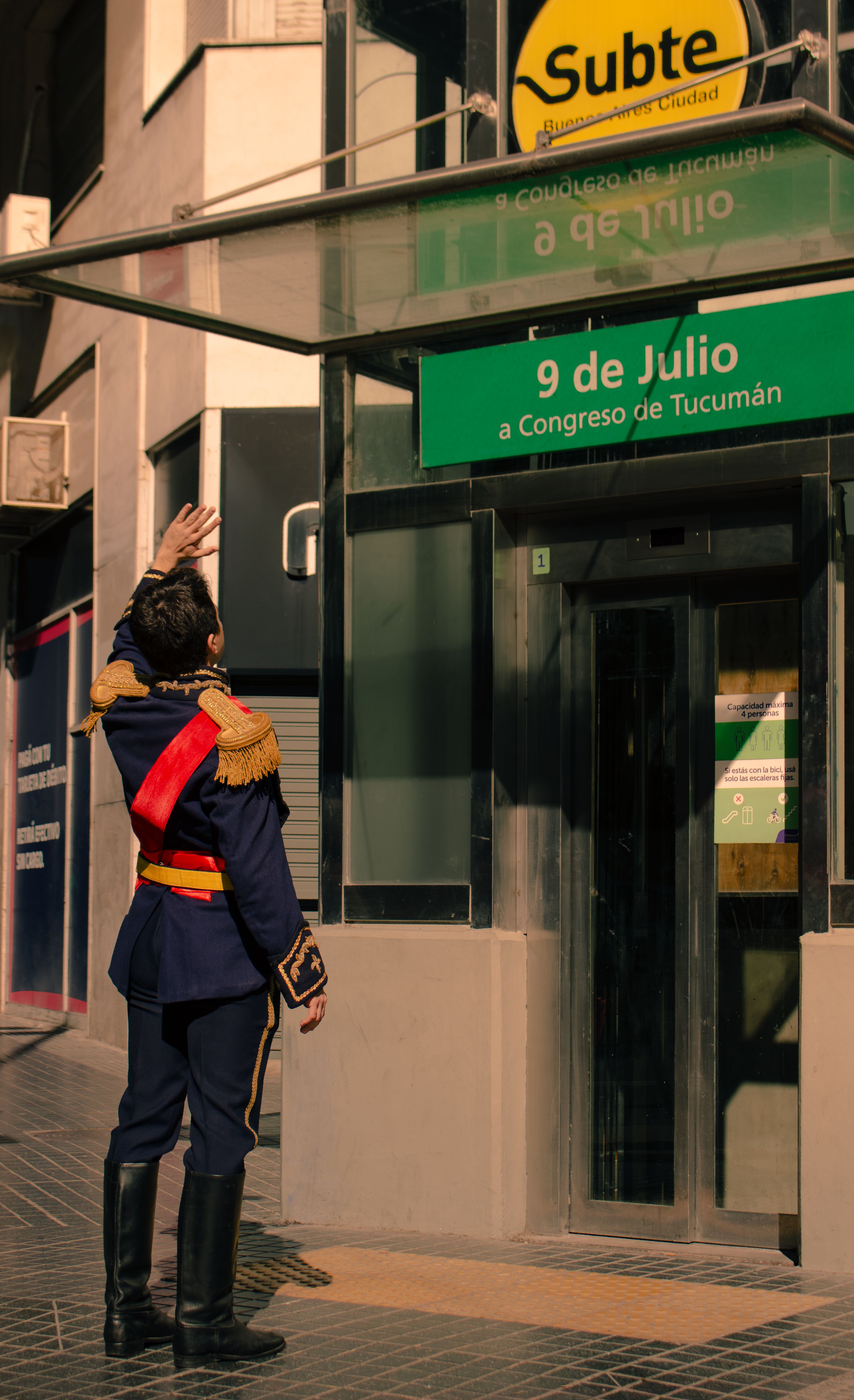 A person in historical attire gestures at the Subte 9 de Julio entrance in Buenos Aires, Argentina.